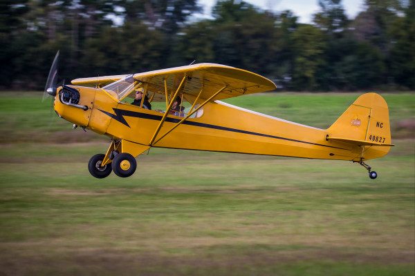 © 2016 Jim Koepnick | Piper Cubs land at slow speeds so are easy to pan. Ed Lachendro and son Ben land their Piper Cub on a grass runway in southern Wisconsin. Sigma 150-600mm Sport; Canon 1DX; 1/160 sec at f5.6; ISO 200.