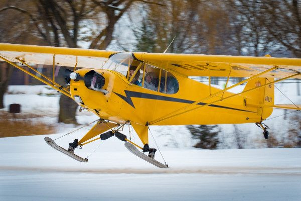© 2016 Jim Koepnick  | Photographing a Piper Cub is not limited to summer. Putting skiis on the airplane is popular in the winter, which gives you year-round shooting opportunities. Sigma 150-600 Sport; Canon 1DX; 1/160 sec at f11; 400 ISO.