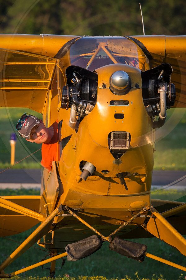© 2016 Jim Koepnick | The human element always adds an extra touch to a photograph. Luke Lachendro looks out for a better view before he shuts the engine down on his Piper Cub. Sigma 150-600 Sport at 420mm; Canon 1DX; 1/30 sec (on tripod) at f10; ISO 100.
